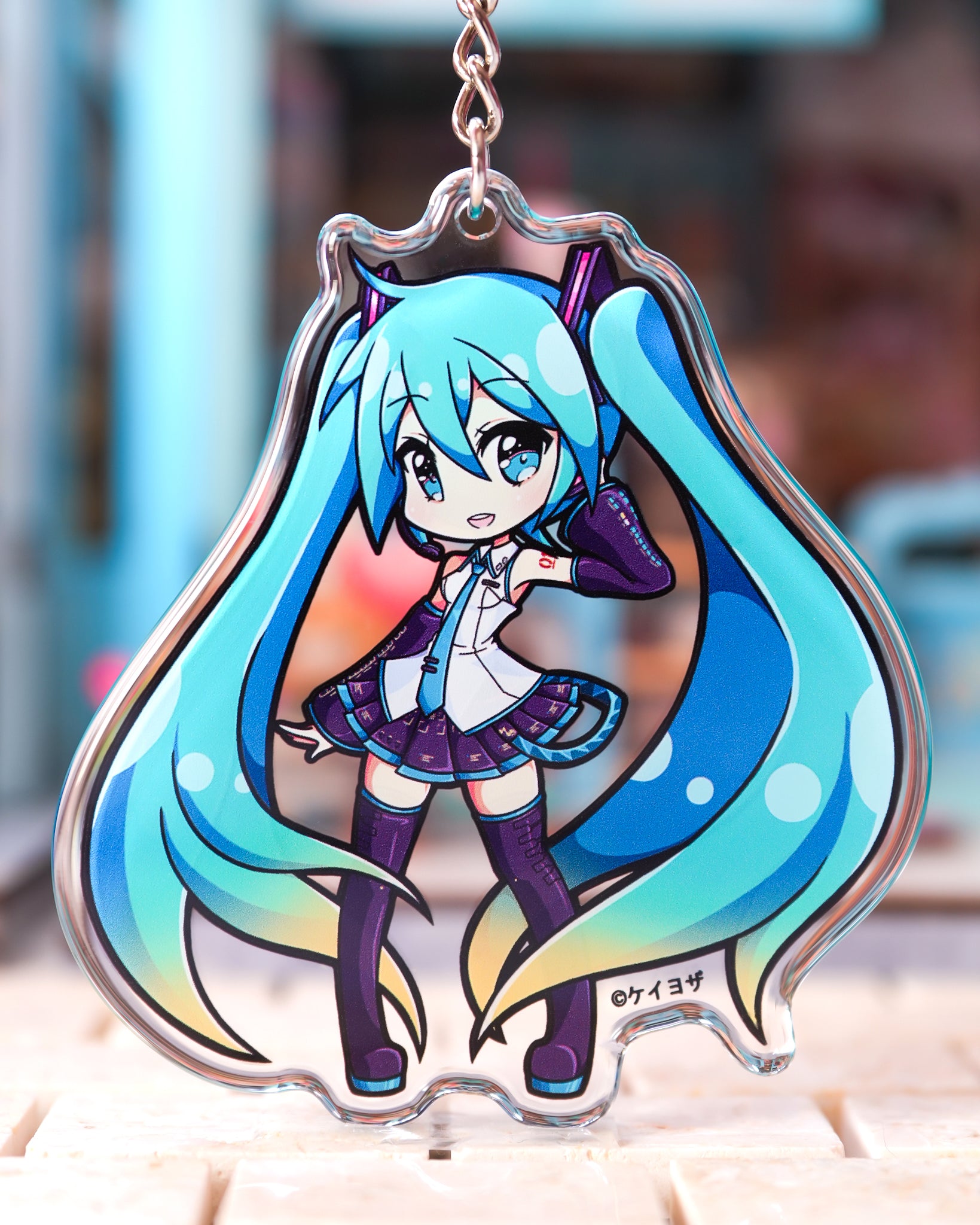 Anime character keychain with blue hair and purple outfit on a blurred background Hatsune miku acrylic charm
