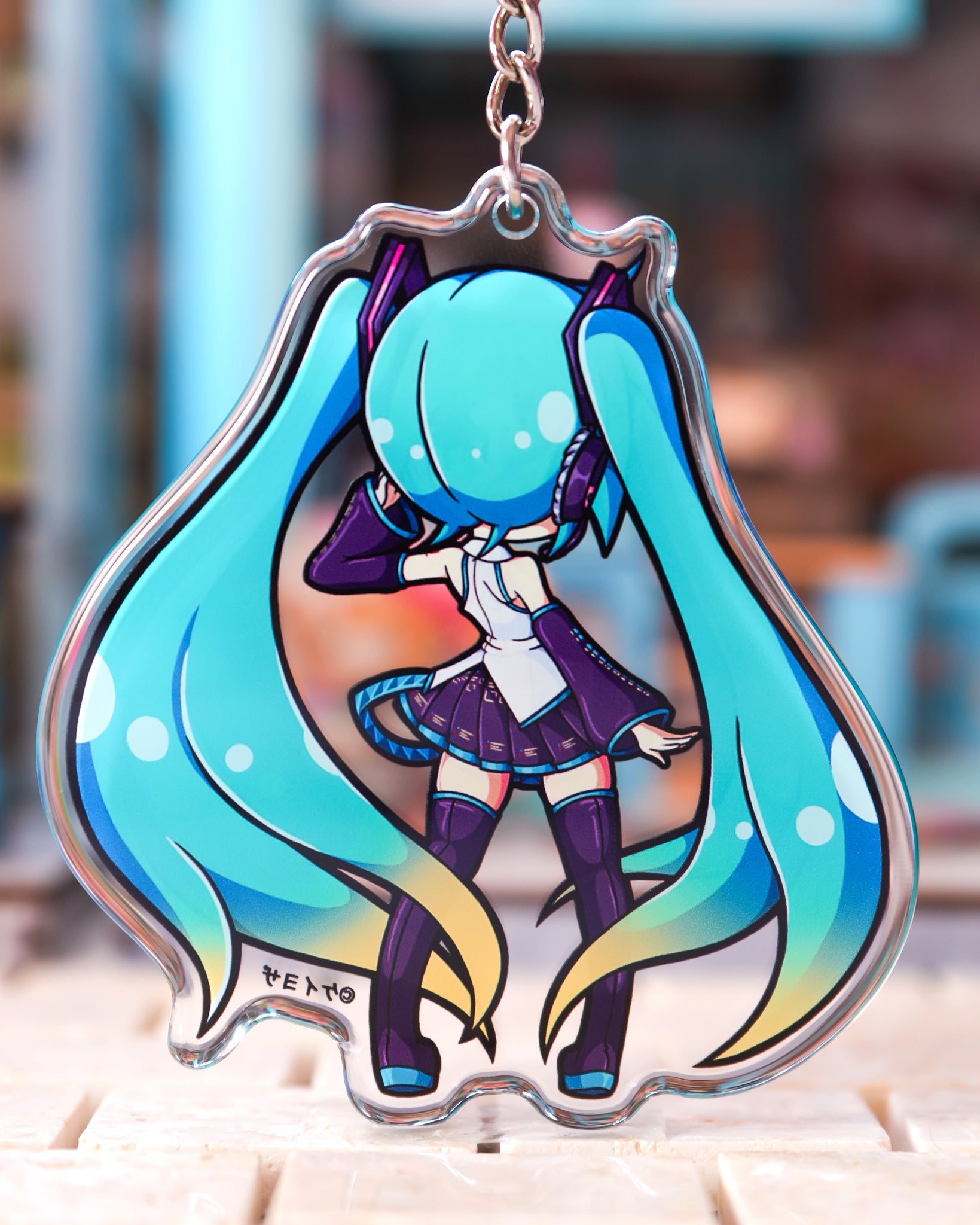 Anime character keychain with vibrant colors on a blurred background