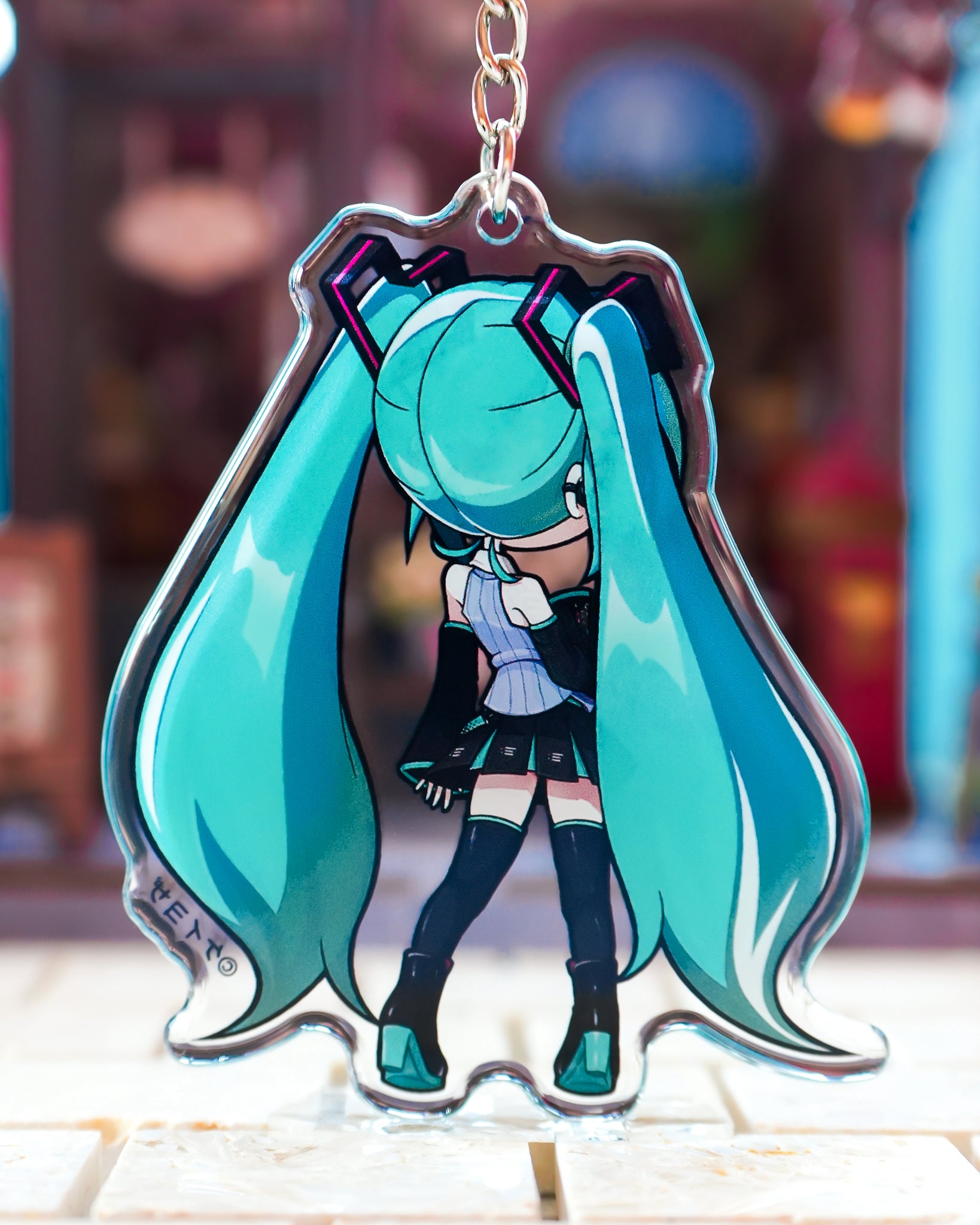 Anime character keychain with long turquoise hair and a blurred background Hatsune miku v6 acrylic charm chibi art